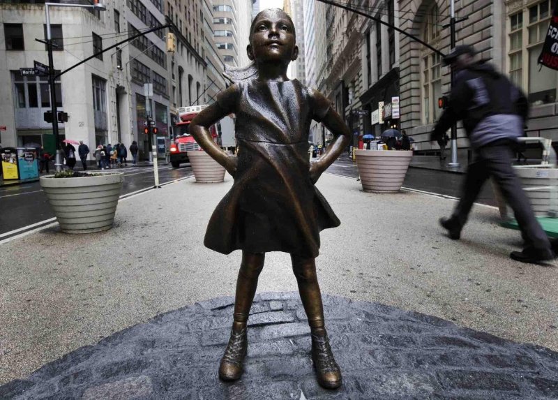 En la imagen un registro de la estatua "The Fearless Girl" (lit. La chica valiente), del artista Kristen Visbal, frente a la famosa escultura del Toro de Wall Street, en Manhattan