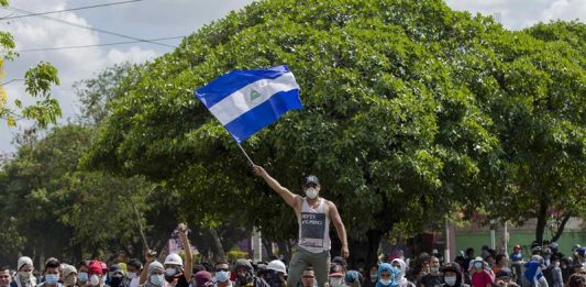 Un joven levanta una bandera de Nicaragua sobre una barricada de adoquines durante el cuarto día de protestas en Managua (Nicaragua).