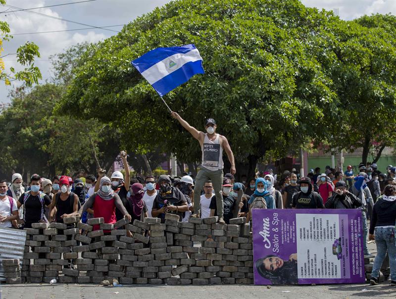 Un joven levanta una bandera de Nicaragua sobre una barricada de adoquines durante el cuarto día de protestas en Managua (Nicaragua).