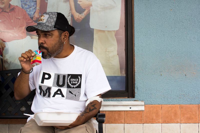 Garc&iacute;a toma un jugo fuera del Fresenius Kidney Care en Humacao, Puerto Rico, despu&eacute;s de recibir di&aacute;lisis. Su comida, que provee Renal Council, una organizaci&oacute;n local sin fines de lucro, incluye arroz, carne roja y vegetales. (Carmen Heredia Rodriguez/KHN)