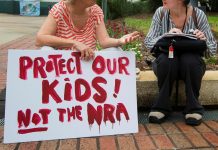 Una mujer sostiene una pancarta en la que se puede leer "proteged a nuestros hijos, no a la NRA"