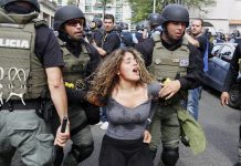 Unos policías antidisturbios detienen a una manifestante, durante la marcha del Día Internacional del Trabajador el martes 1 de mayo de 2018, en San Juan (Puerto Rico).