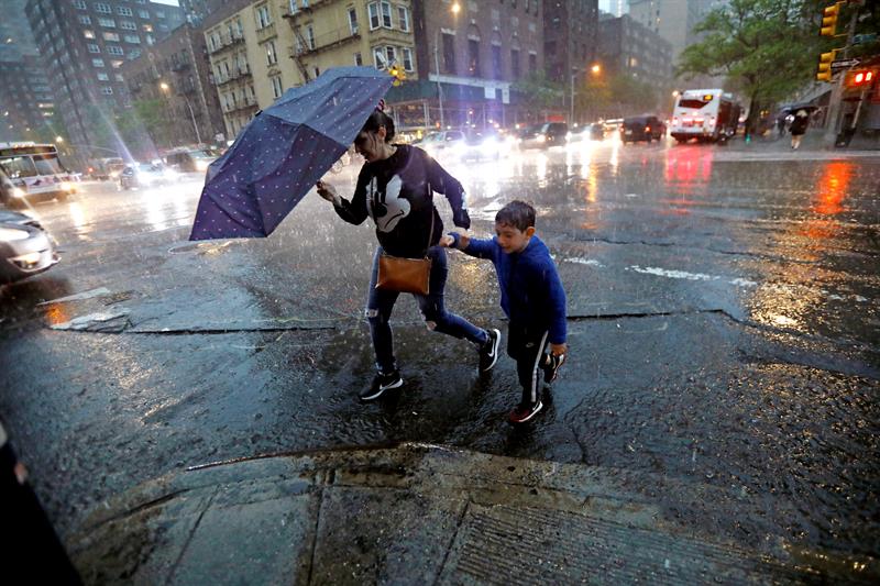 Una mujer cruza la calle con un ni&ntilde;o durante una tormenta en Nueva York el martes 15 de mayo de 2018.