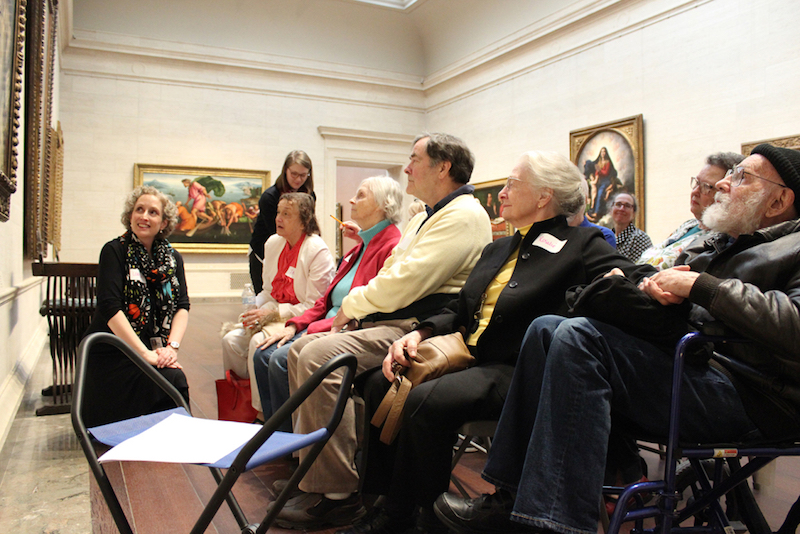 Lorena Bradford (izq.), de la National Gallery of Art, en Washington, D.C., lidera una sesi&oacute;n del programa Just Us, el 5 de marzo, con un grupo de pacientes de Alzheimer y sus cuidadores. El programa genera discusiones sobre obras de arte. (Lynne Shallcross/KHN)