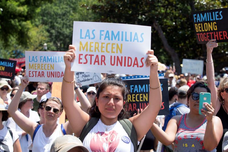 Participante sostiene un letrero durante el mitin de "Familias que pertenecen juntas" en el parque Lafayette frente a la Casa Blanca (atrás) en Washington, DC