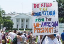 Miles de personas exigen reunir a las familias de inmigrantes Participantes sostiene un letrero durante el mitin de "Familias que pertenecen juntas" en el parque Lafayette frente a la Casa Blanca (atrás) en Washington, DC.