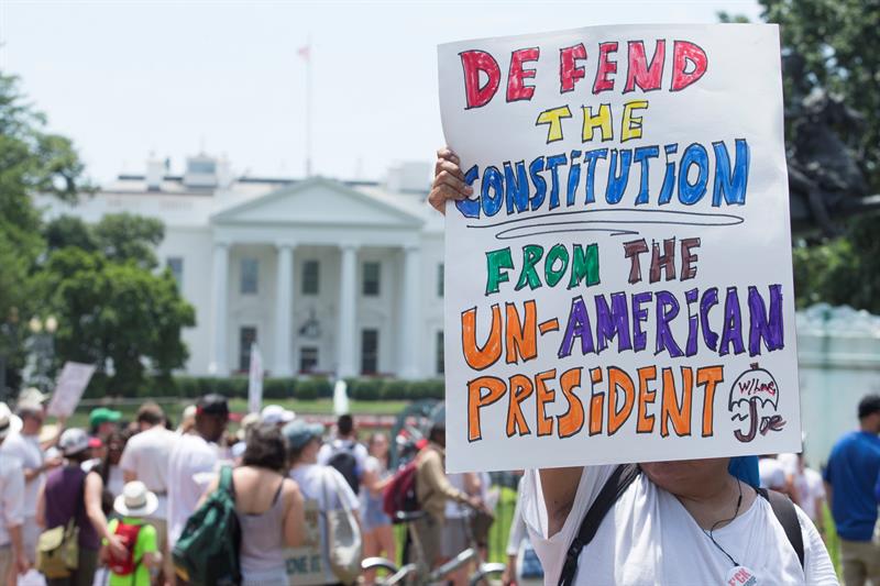Participantes sostiene un letrero durante el mitin de "Familias que pertenecen juntas" en el parque Lafayette frente a la Casa Blanca (atrás) en Washington, DC.