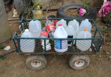 Elba Negrón Carreras utiliza botellas de plástico y leche para cargar agua. Ella y sus dos hijos deben caminar media hora hasta una estación para llevar a casa agua potable para cocinar, beber y hasta para ducharse. (Carmen Heredia Rodriguez/Kaiser Health News)