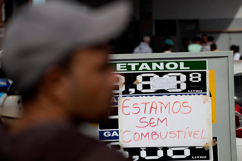 Una persona pasa frente a un cartel donde est&aacute; escrito "estamos sin combustible", en una estaci&oacute;n de servicio.