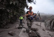 El volcán de Fuego de Guatemala causa 25 muertos y 1,7 millones de afectados Un trabajador de los equipos de rescate de Guatemala ayuda a una niña en El Rodeo, Escuintla (Guatemala) ayer domingo 3 de junio de 2018, luego de la erupción del volcán de Fuego.