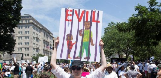 Una mujer con un letrero se une a miles de personas que asisten a una concentración de 'Families Belong Together' en el Parque Lafayette frente a la Casa Blanca en Washington, DC
