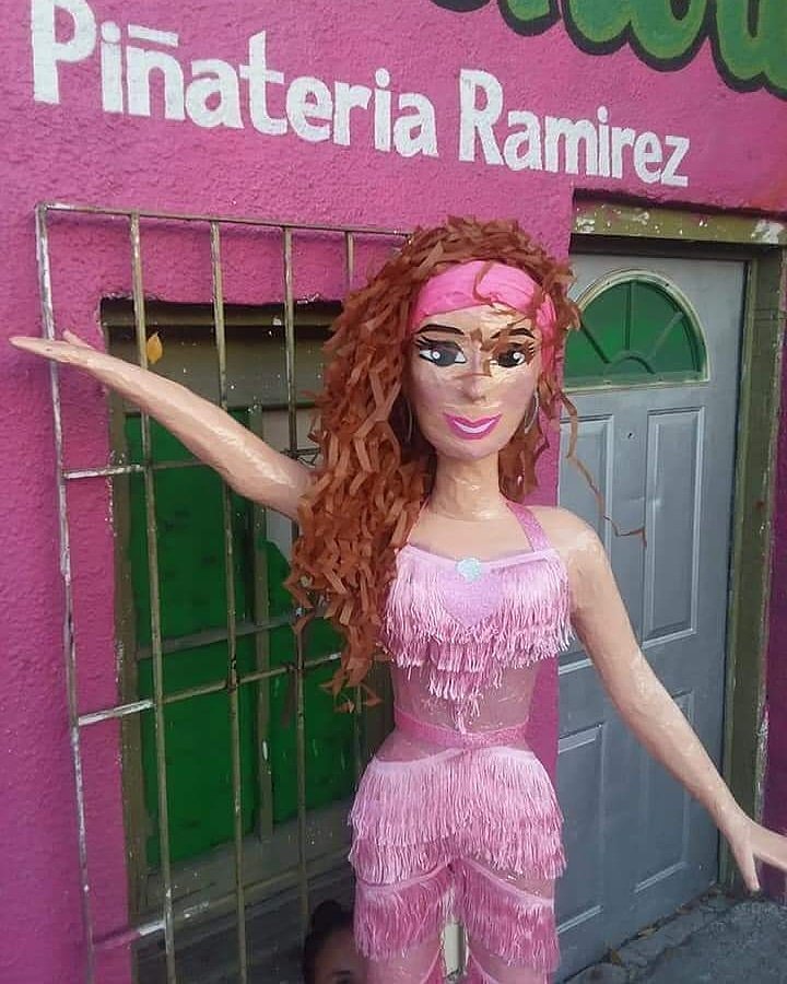 En la piñata, la cantante aparece vestida con un mono rosa de flecos, con una cinta en la cabeza del mismo color, grandes pendientes y el pelo suelto echado a un lado