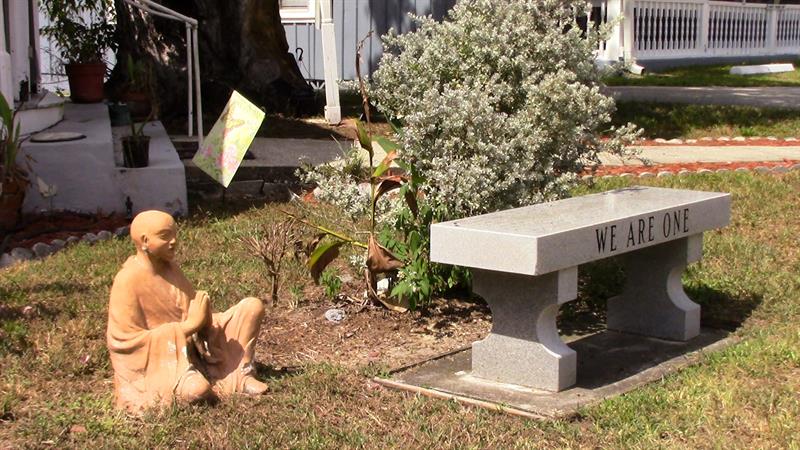figura de un monje budista y la leyenda "Somos uno" escrita sobre un banco en una de las calles de Cassadaga
