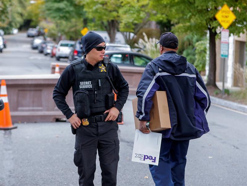 Un miembro del Servicio Secreto de los Estados Unidos (i) habla con un repartidor cerca de la residencia del expresidente estadounidense Barack Obama en Washington, Estados Unidos, hoy, 24 de octubre de 2018. 