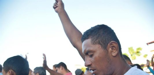 Migrantes hodureños realizan un minuto de silencio en memoria de del migrante que cayó de un transporte el día de ayer cuando se movilizaban hacia la población de Huixtla, en el estado de Chiapas (México), durante su travesía hacia Estados Unidos hoy, martes 23 de octubre de 2018.