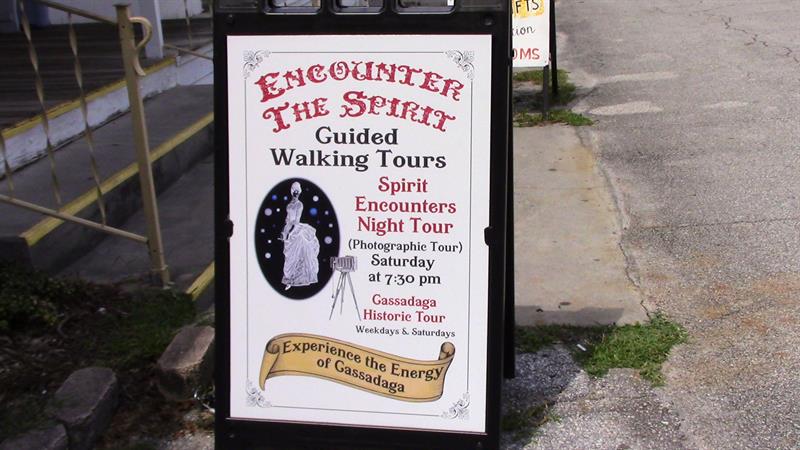 cartel que anuncia visitas guiadas y encuentros con espiritistas desplegado en una de las calles de Cassadaga