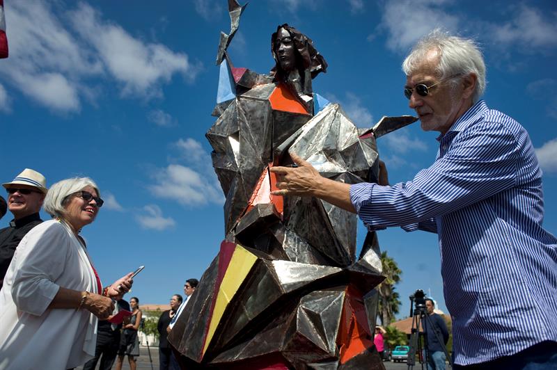 Jim Bliesner (d) posa junto a una r&eacute;plica en miniatura de su obra "Bienvenido al Extra&ntilde;o", que retrata a la virgen Mar&iacute;a sujetando una antorcha y ataviada con una t&uacute;nica de acero