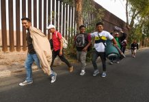Decenas de migrantes centroamericanos caminan hoy junto a la valla fronteriza de la ciudad norteña de Mexicali rumbo a la ciudad de Tijuana (México).