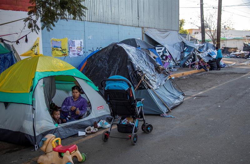 Migrantes duermen hoy a la intemperie fuera del albergue original que resultó inhabitable luego de las fuertes lluvias en Tijuana (México).