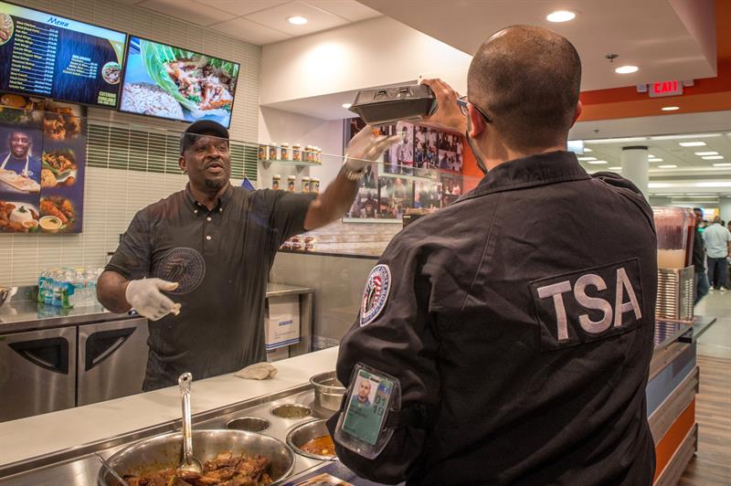 Un agente de la Administraci&oacute;n de Seguridad del Transporte (TSA) recibe comida gratuita de manos de Wilkinson Sejour, due&ntilde;o de Chef Cr&eacute;ole.