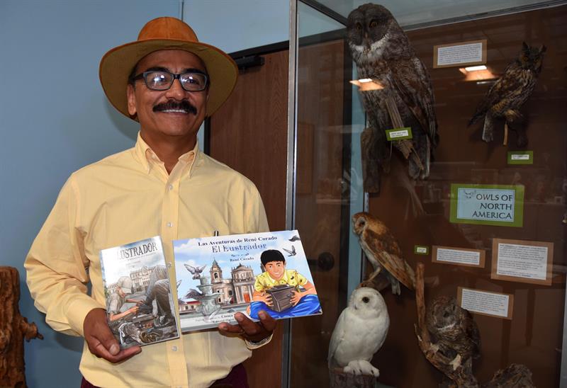 René Corado, mientras muestra su libro "El ilustrador" y su versión infantil "Las aventuras de René Corado, el lustrador".