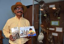 René Corado, mientras muestra su libro "El ilustrador" y su versión infantil "Las aventuras de René Corado, el lustrador".
