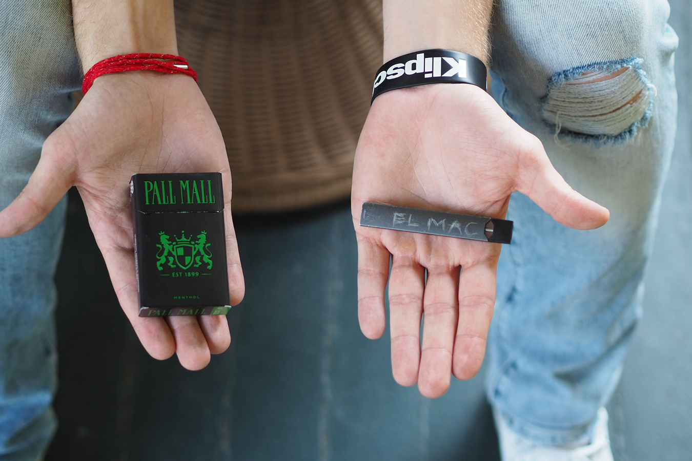 Lucas McClain sostiene una cajetilla de cigarillos y su Juul, en su casa de Arlington, Virginia. McClain volvi&oacute; a fumar cigarrillos con la esperanza de dejar el h&aacute;bito de Juul. (Lynne Shallcross/KHN)
