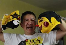 El fabricante de máscaras de luchador, Pedro Rosas Kenjiro, posa con dos máscaras.