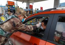 Un miembro de la milicia verifica la temperatura corporal de un conductor en un vehículo en una autopista de peaje en Wuhan, provincia de Hubei, en el centro de China, el 23 de enero de 2020.