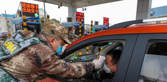 Un miembro de la milicia verifica la temperatura corporal de un conductor en un vehículo en una autopista de peaje en Wuhan, provincia de Hubei, en el centro de China, el 23 de enero de 2020.
