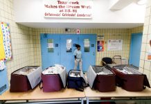 Una mujer espera en la puerta del colegio 234 de Queens para recoger la comida que desde este viernes ofrece el Ayuntamiento de Nueva York a toda persona que lo necesite