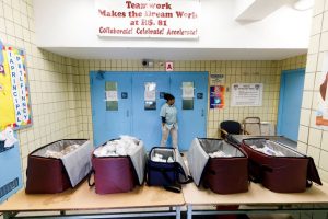 Una mujer espera en la puerta del colegio 234 de Queens para recoger la comida que desde este viernes ofrece el Ayuntamiento de Nueva York a toda persona que lo necesite