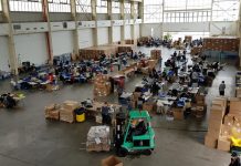 Sentados en varias hileras de mesas entre el eco de las voces, el ruido de la manufacturación en cadena y de la música proveniente de los altavoces de algunos de los voluntarios, 160 personas fabrican entre 25.000 y 30.000 máscaras protectoras al día.