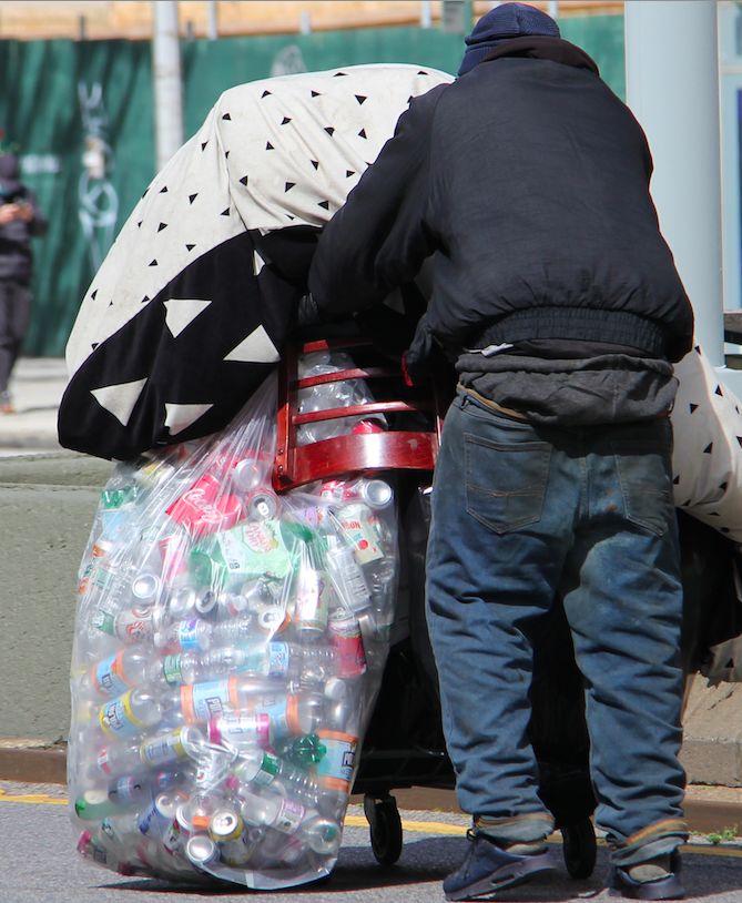 Mendigos recolectando latas y botellas para subsistencia.