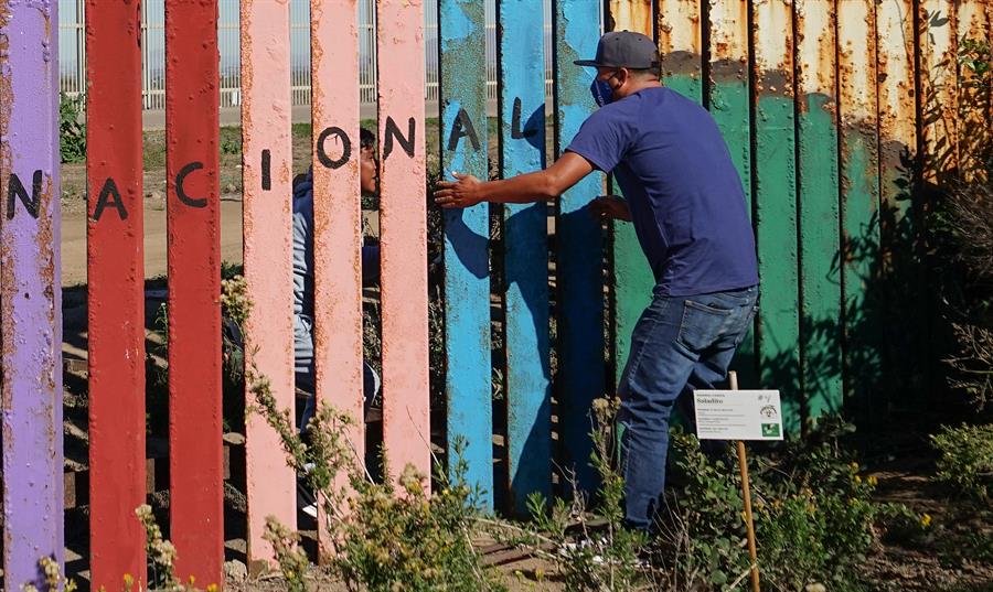 Dos personas hablan a trav&eacute;s de una valla fronteriza entre M&eacute;xico y Estados Unidos el 30 de junio de 2022, en Tijuana (M&eacute;xico). 
