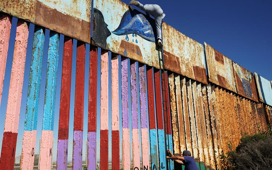  Una persona ayuda a cruzar la frontera hacia Estados Unidos a un migrante el 30 de junio de 2022, en Tijuana (M&eacute;xico). 