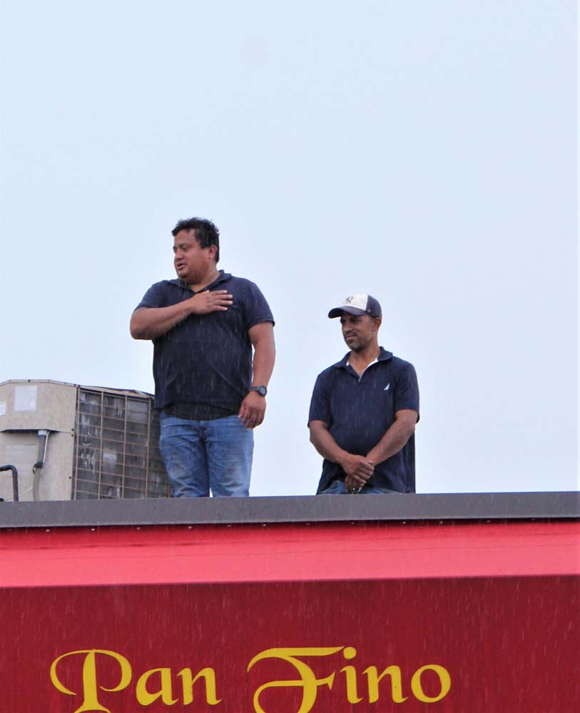 Los ecuatorianos bajo la lluvia, aun desde el techo de las casas, cantaron su Himno Nacional.