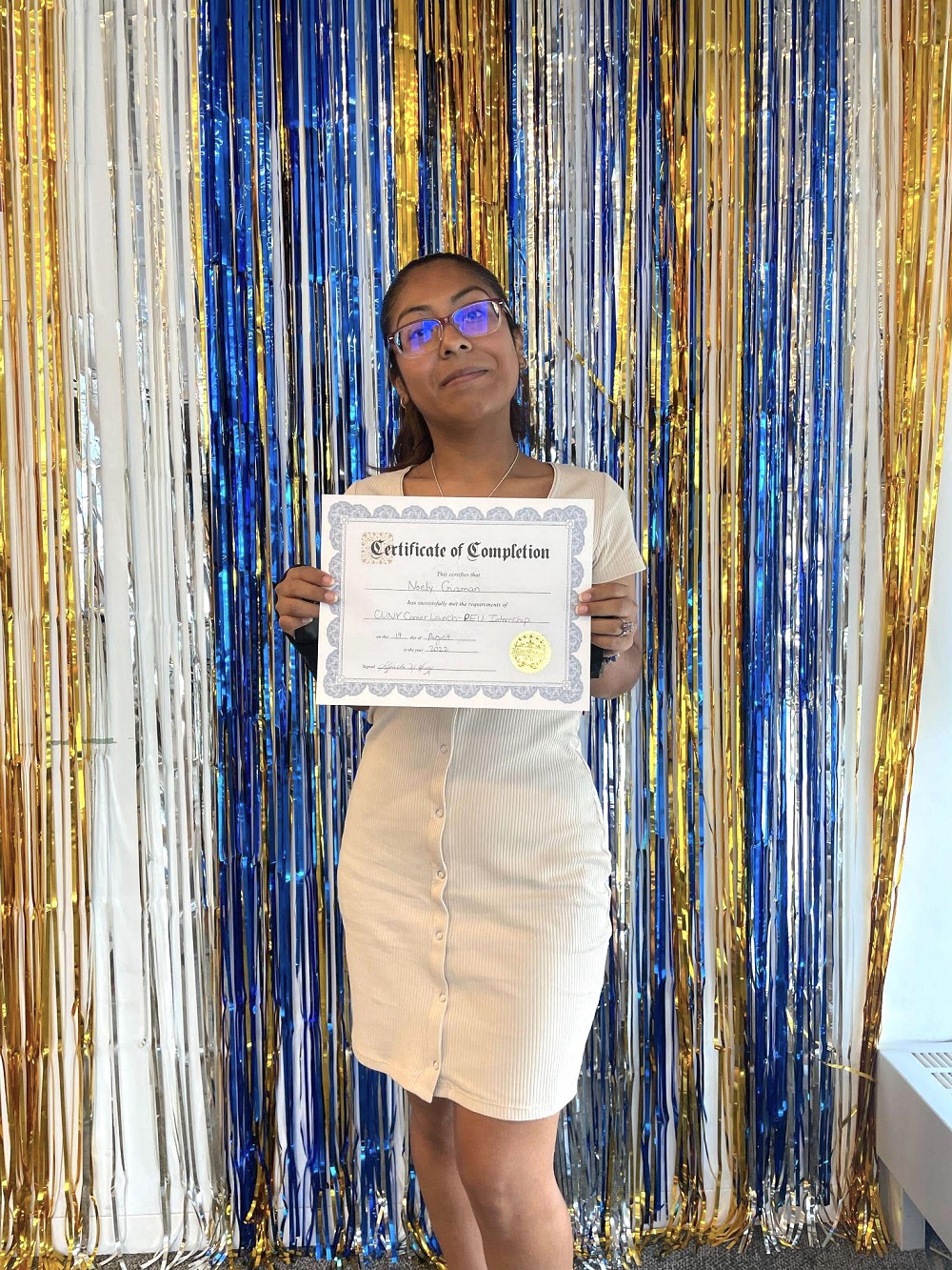 Otra estudiante de CUNY, Noely Guzmán, posa con su Certificado de finalización de la pasantía, durante la despedida organizada por esa Unidad de Compromiso Público de la Alcaldía (PEU).