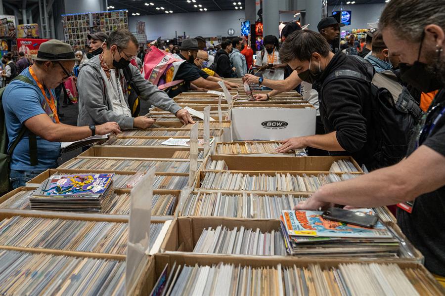 Personas ojean los cómics guardados en cajas de uno de los puestos de la feria Comic Con
