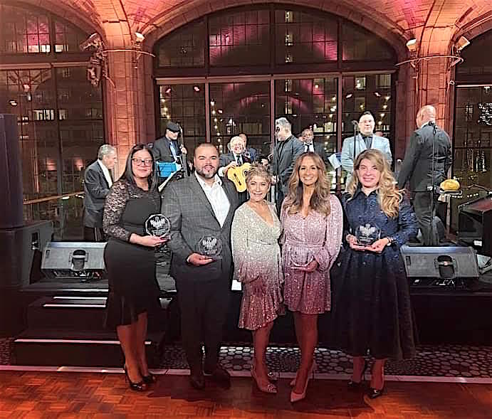 Los reconocidos durante la gala del 25o aniversario de la organización 100 Hispanic Women rodeando a su presidente, Doña Nancy Génova durante el evento que fue amenizado por una banda en vivo.