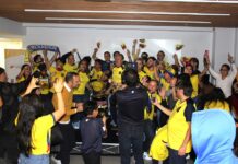 Hinchas ecuatorianos saltando, gritando y bailando en la tarima del salón general del consulado.)