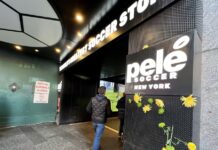 Un hombre pasa delante de unas flores colgadas hoy, en la entrada de la tienda Pelé Soccer situada en la icónica plaza de Times Square, en Nueva York (EEUU).