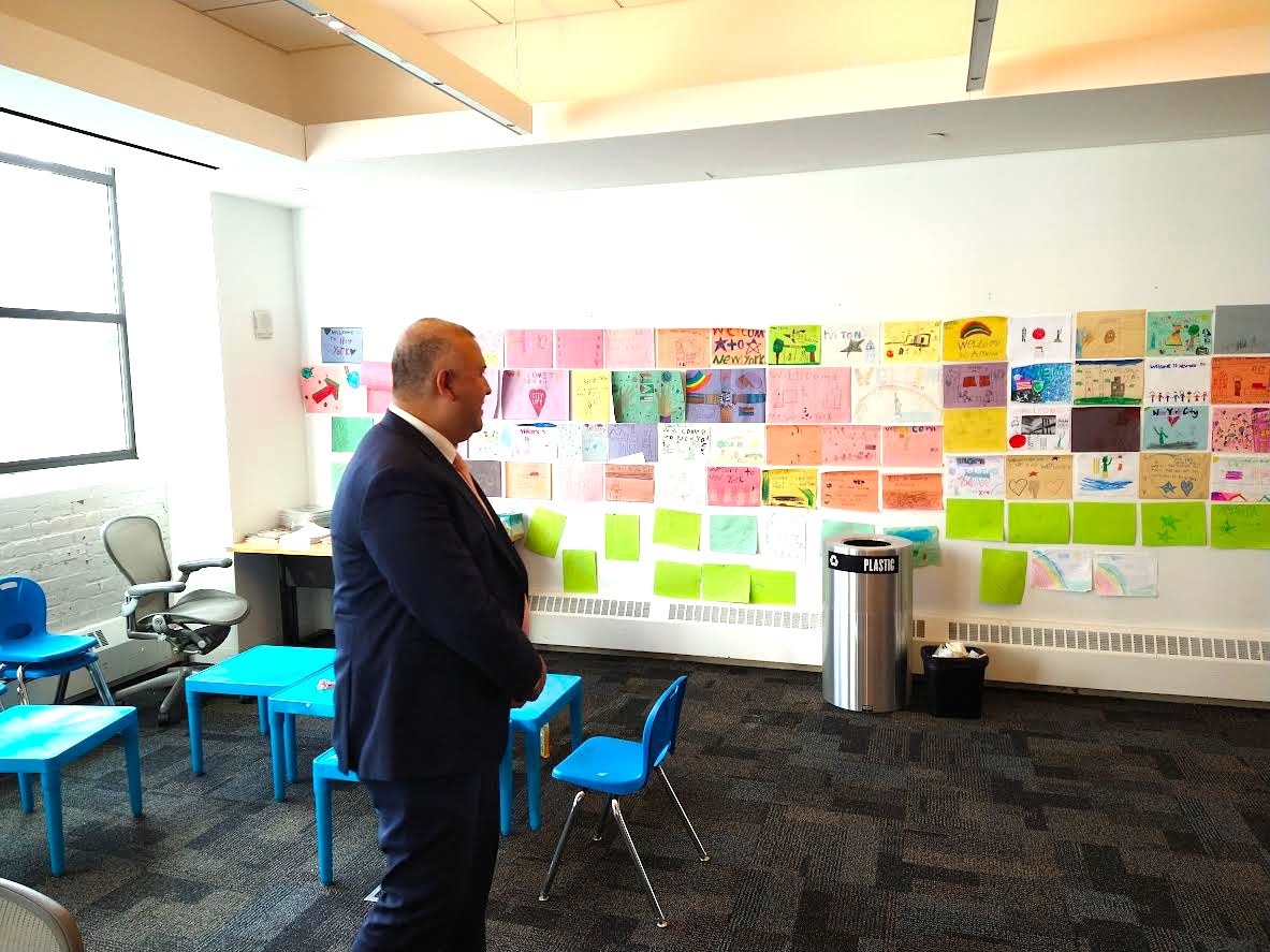 El comisionado Manuel Castro con mucha alegr&iacute;a observa los dibujos realizados por los ni&ntilde;os de las escuelas p&uacute;blicas de Nueva York, en los cuales dan la bienvenida a los refugiados que llegan huyendo de la violencia, de la persecuci&oacute;n y de la pobreza extrema, como lo han hecho millones desde el inicio de la ciudad en 1625.