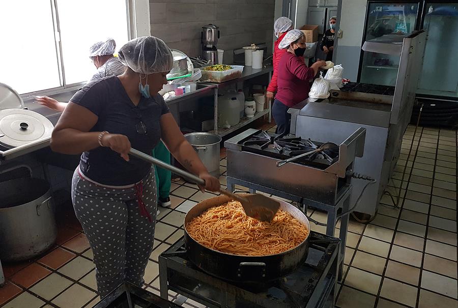 Personas preparan alimentos para migrantes que permanecen en un albergue