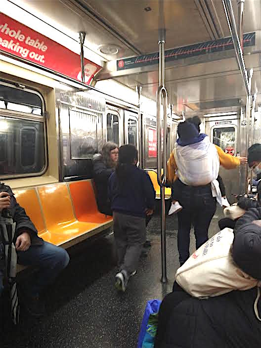 Una inmigrante latina con su niño pequeño en la espalda y otro menor, recorre la línea del tren 1 en Manhattan ofreciendo dulces a los pasajeros.