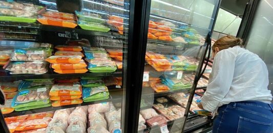 Una persona compra pollo en una tienda de autoservicio