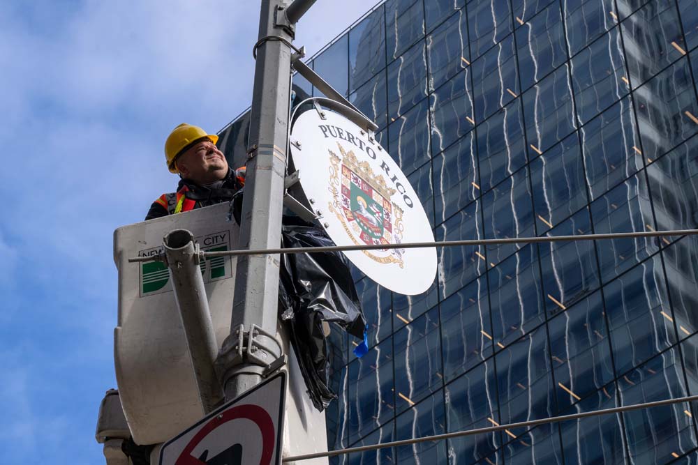 Un trabajador del Departamento de Transporte de Nueva York instala en un poste el escudo dedicado a Puerto Rico durante el acto de instalaci&oacute;n de escudos alusivas a pa&iacute;ses latinoamericanos en la Avenida de las Am&eacute;ricas en Nueva York.