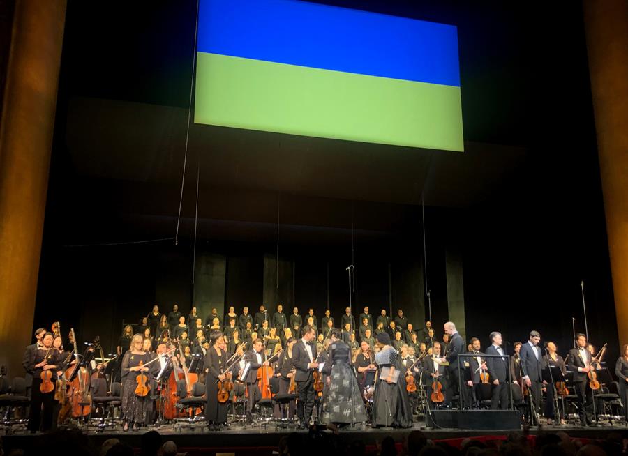 La orquesta y coro de la Filarm&oacute;nica de Nueva York, bajo una bandera ucraniana, interpretan un concierto a favor de ese pa&iacute;s, cuando se marca el primer aniversario de la invasi&oacute;n rusa, hoy, en Nueva York (EE.UU.).