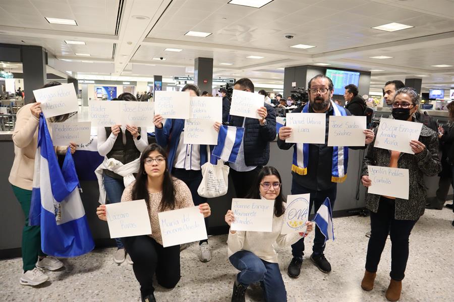 Personas sostienen banderas nicaragüenses a la espera de la llegada de los presos políticos expulsados de ese país (1)