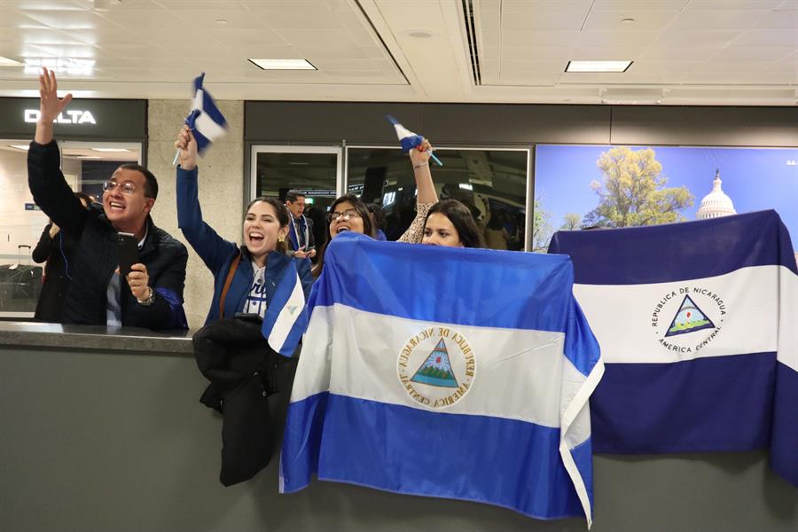 Personas sostienen banderas nicaragüenses a la espera de la llegada de los presos políticos expulsados de ese país (2)